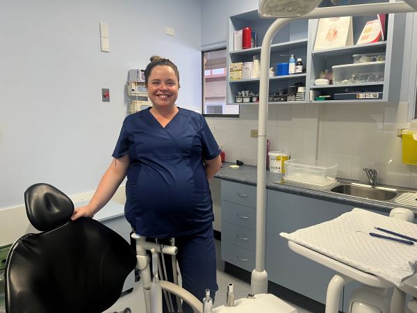 Dental Assistant smiling and standing next to dentist chair